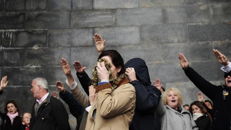 Une femme se cache le visage alors qu’elle effectue un salut fasciste avec d’autres personnes, après avoir assisté à une messe, près de la basilique de Valle de los Caidos, près de Madrid, en novembre 2011.